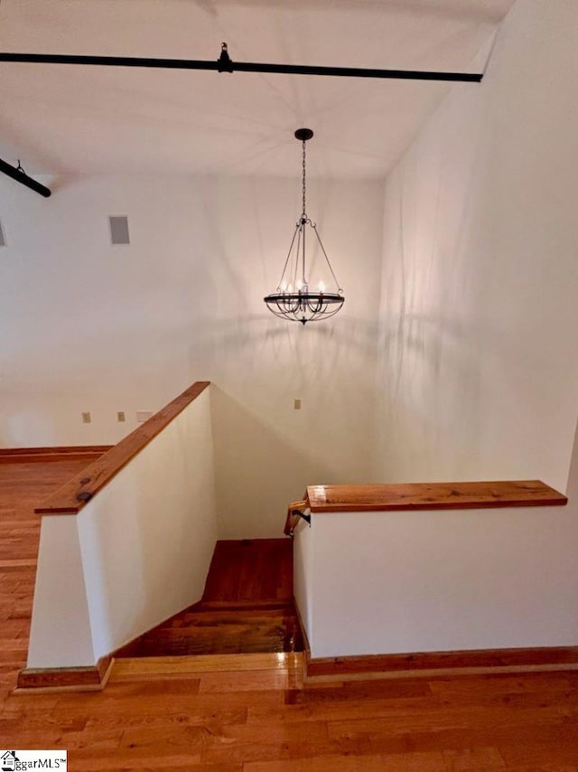 stairs featuring a chandelier and hardwood / wood-style flooring