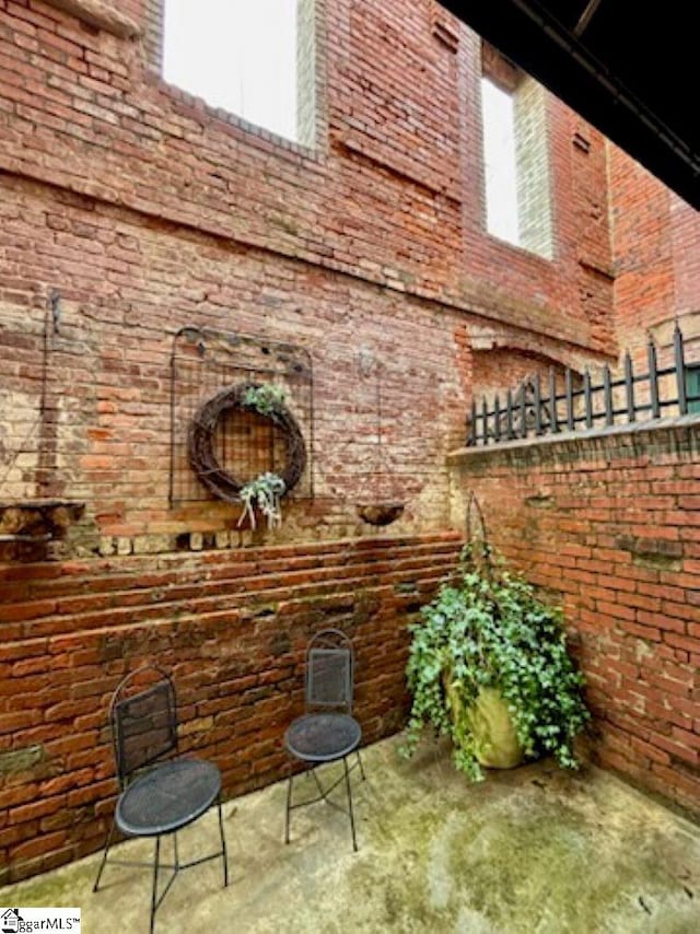 bar with concrete flooring, a towering ceiling, plenty of natural light, and brick wall