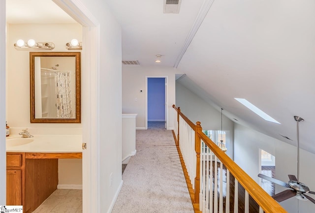 hallway featuring sink, light colored carpet, and lofted ceiling