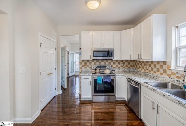 kitchen with decorative backsplash, white cabinetry, dark hardwood / wood-style flooring, and stainless steel appliances