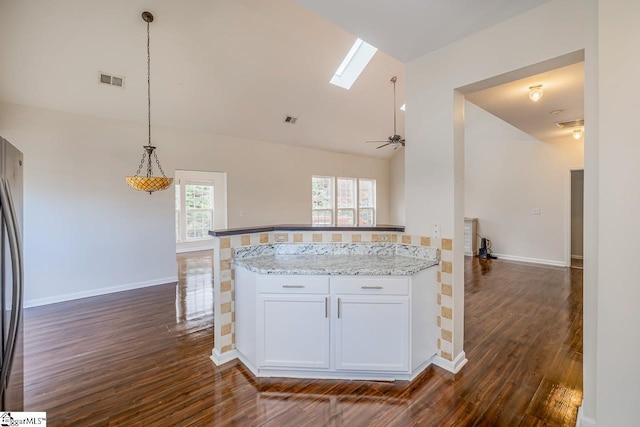 kitchen with a skylight, light stone counters, ceiling fan, dark wood-type flooring, and white cabinets