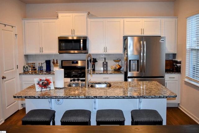 kitchen featuring backsplash, sink, dark stone countertops, appliances with stainless steel finishes, and white cabinetry