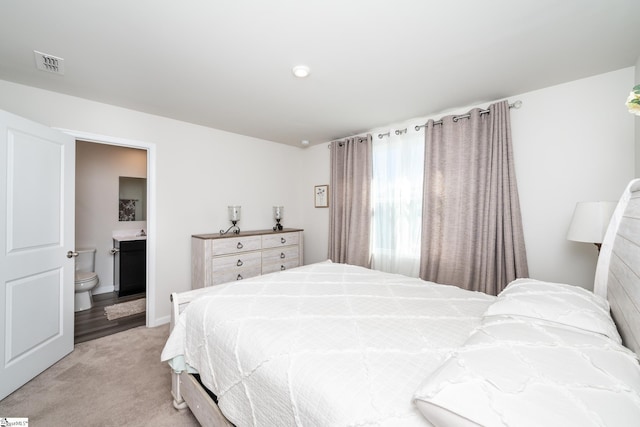 bedroom featuring ensuite bathroom and light carpet