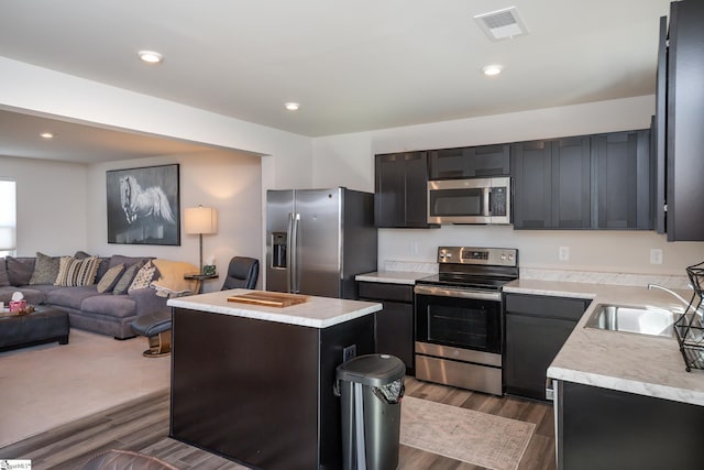 kitchen with sink, dark wood-type flooring, a kitchen island, and appliances with stainless steel finishes