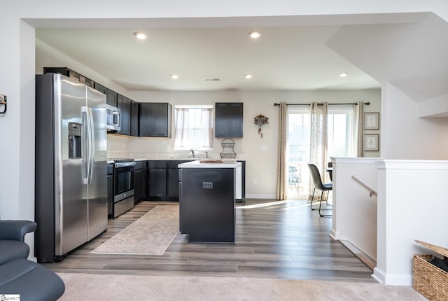 kitchen with a kitchen island, appliances with stainless steel finishes, sink, and light hardwood / wood-style floors