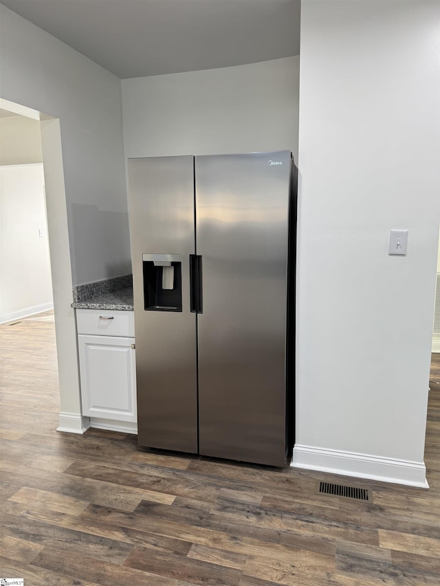 kitchen with light stone counters, dark hardwood / wood-style floors, white cabinets, and stainless steel refrigerator with ice dispenser