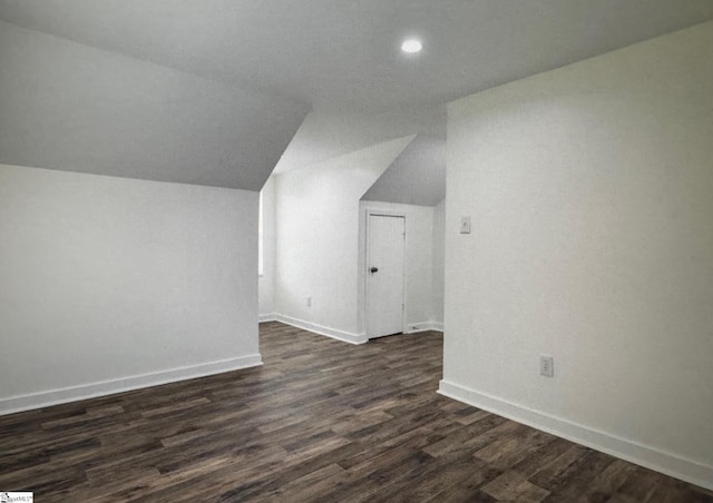 additional living space featuring dark wood-type flooring and vaulted ceiling