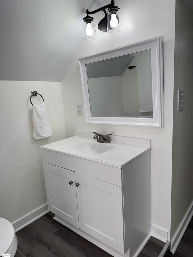 bathroom featuring vanity, vaulted ceiling, toilet, and wood-type flooring