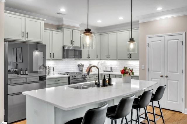 kitchen featuring a kitchen bar, an island with sink, decorative light fixtures, and appliances with stainless steel finishes