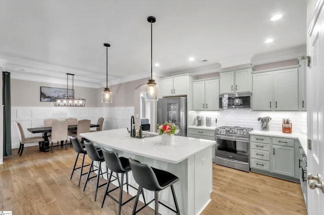 kitchen featuring pendant lighting, a breakfast bar, sink, light hardwood / wood-style floors, and stainless steel appliances