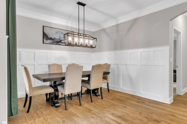 dining space with light hardwood / wood-style floors, ornamental molding, and a notable chandelier