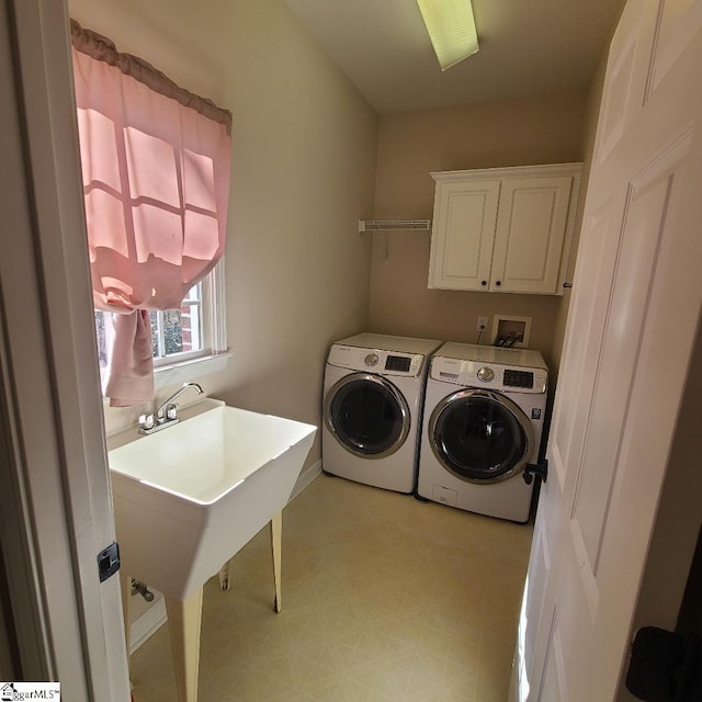 clothes washing area with washer and clothes dryer, cabinets, and sink