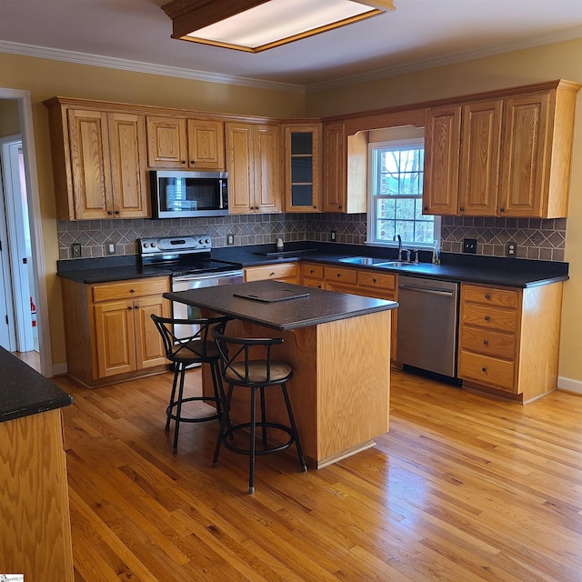 kitchen featuring a kitchen island, light wood-type flooring, backsplash, and appliances with stainless steel finishes