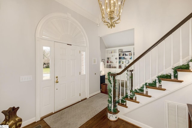 foyer with dark hardwood / wood-style flooring, ornamental molding, and an inviting chandelier