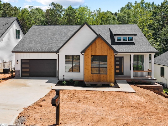 view of front of property featuring central AC, covered porch, and a garage