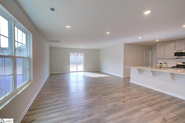 unfurnished living room with sink and light hardwood / wood-style floors