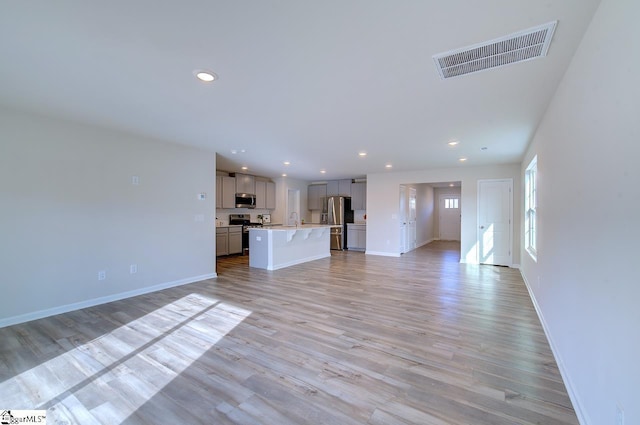 unfurnished living room with light hardwood / wood-style floors and sink