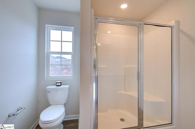 bathroom featuring wood-type flooring, a shower with shower door, and toilet