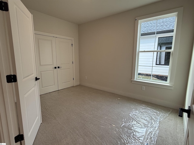 unfurnished bedroom with a closet and light colored carpet