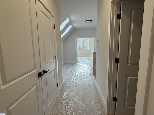 hallway with vaulted ceiling with skylight