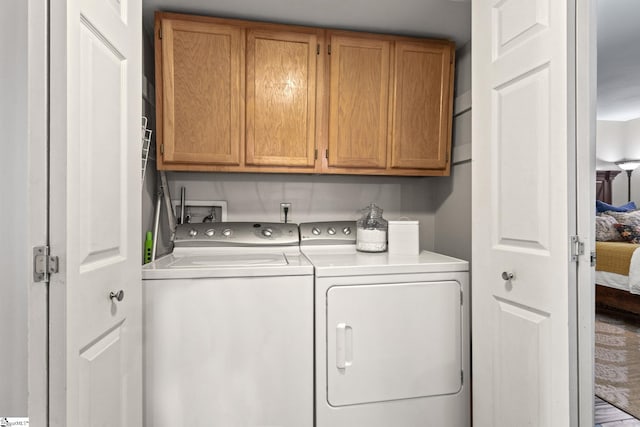 clothes washing area with washer and dryer and cabinets