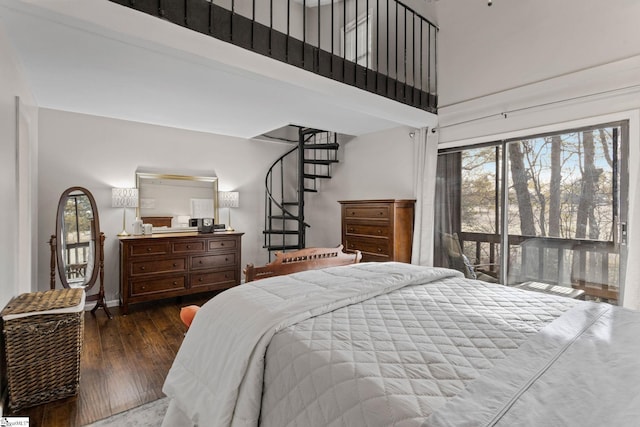 bedroom with dark hardwood / wood-style floors, access to exterior, and a high ceiling