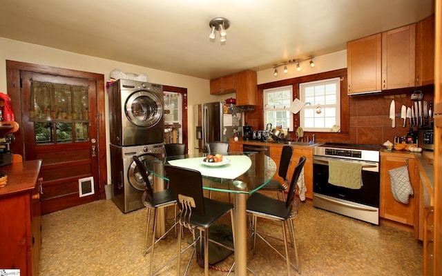 kitchen with tasteful backsplash, stainless steel appliances, and stacked washer and clothes dryer