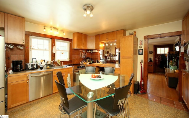 kitchen with sink, stainless steel dishwasher, white refrigerator, backsplash, and light hardwood / wood-style floors