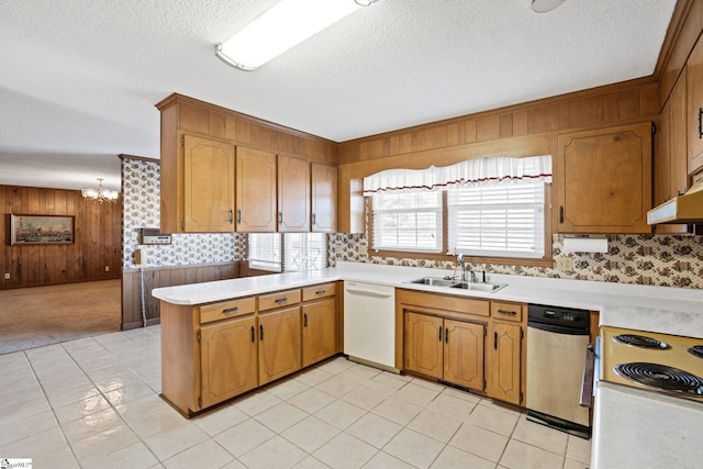 kitchen featuring kitchen peninsula, wooden walls, white dishwasher, a chandelier, and sink