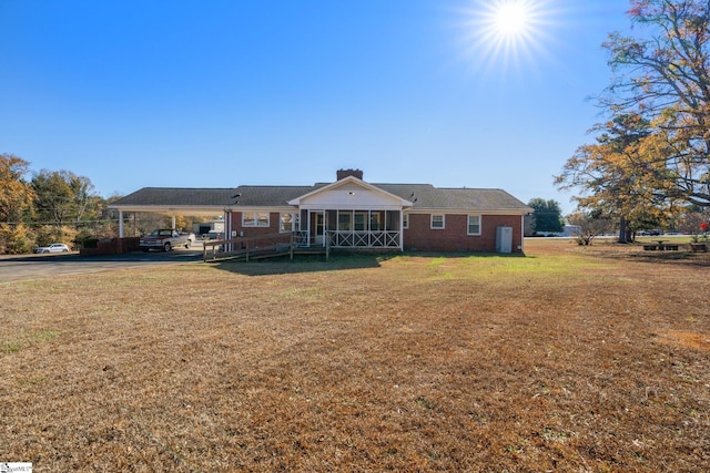 back of house featuring a carport, a yard, and a sunroom