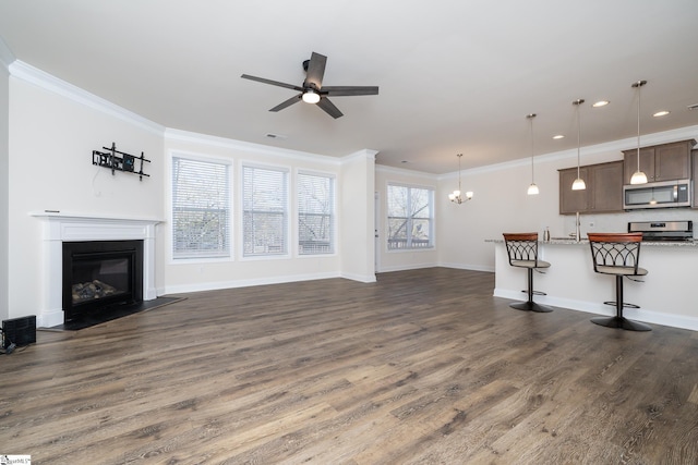 unfurnished living room featuring ceiling fan with notable chandelier, ornamental molding, and dark wood-type flooring