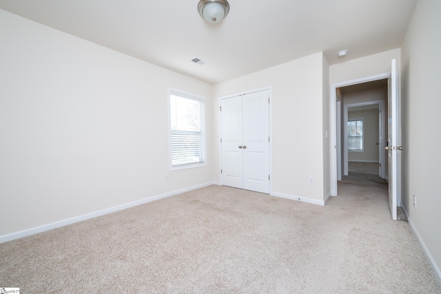 unfurnished bedroom featuring light carpet and a closet