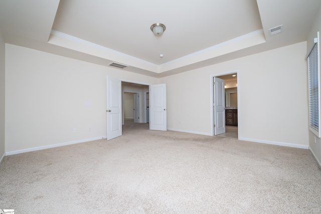 unfurnished bedroom featuring light carpet, connected bathroom, and a raised ceiling