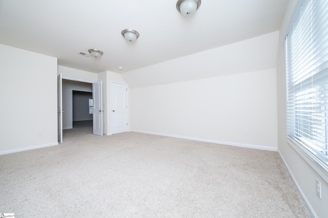 empty room featuring light colored carpet and vaulted ceiling