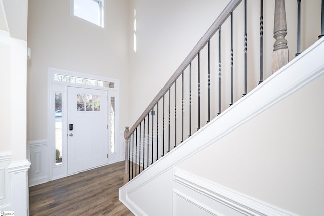 entrance foyer with a high ceiling, a healthy amount of sunlight, and dark hardwood / wood-style floors