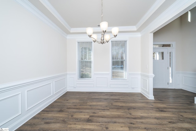 unfurnished dining area with dark hardwood / wood-style floors, ornamental molding, and an inviting chandelier