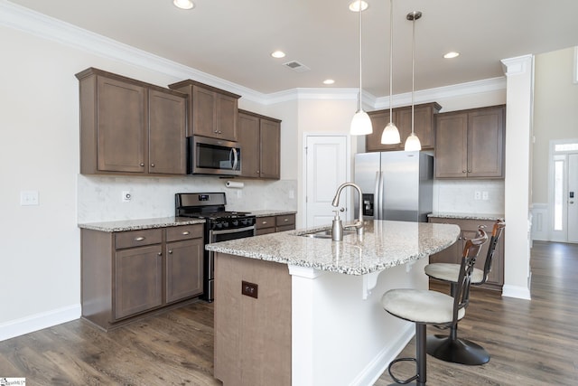 kitchen featuring sink, an island with sink, decorative light fixtures, light stone counters, and stainless steel appliances