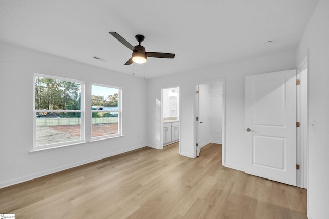 unfurnished bedroom with a walk in closet, light hardwood / wood-style flooring, connected bathroom, and a closet