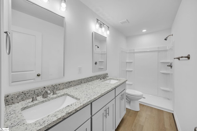 bathroom featuring hardwood / wood-style flooring, vanity, toilet, and walk in shower