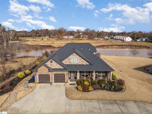 view of front of house with covered porch, a water view, and a garage