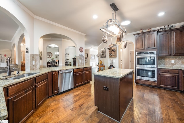 kitchen featuring light stone countertops, sink, stainless steel appliances, dark wood-type flooring, and ornamental molding