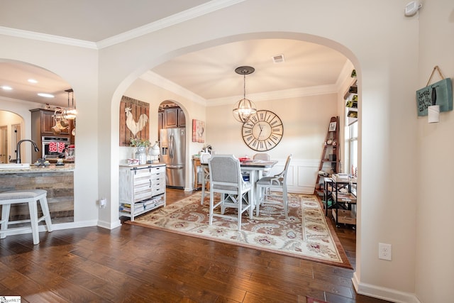 dining area with dark hardwood / wood-style floors, crown molding, and an inviting chandelier