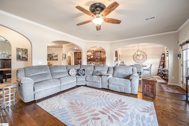 living room with ceiling fan with notable chandelier, dark hardwood / wood-style floors, and crown molding