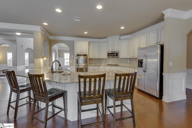 kitchen with dark hardwood / wood-style flooring, a breakfast bar, stainless steel appliances, crown molding, and a large island