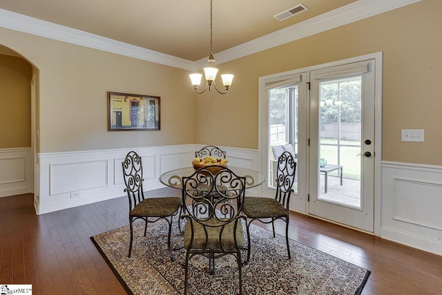 dining space with crown molding, dark hardwood / wood-style floors, and an inviting chandelier