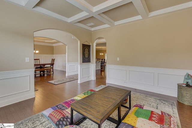 living room featuring dark hardwood / wood-style flooring, coffered ceiling, crown molding, beam ceiling, and a chandelier