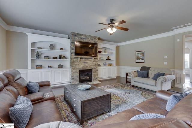 living room with a stone fireplace, crown molding, built in features, and wood-type flooring