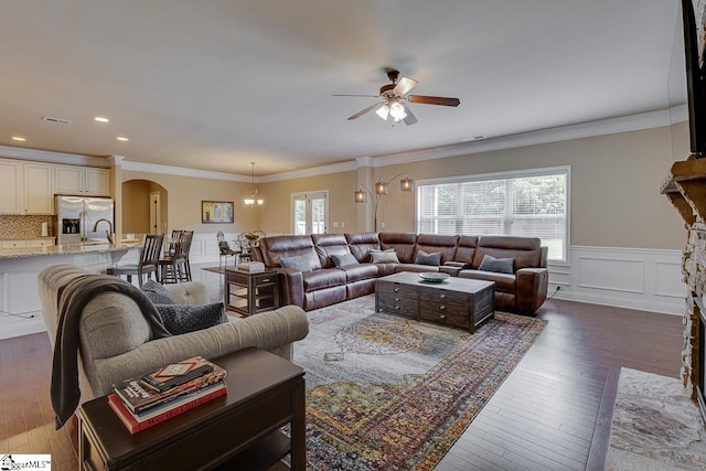 living room featuring ceiling fan with notable chandelier, dark hardwood / wood-style flooring, and ornamental molding