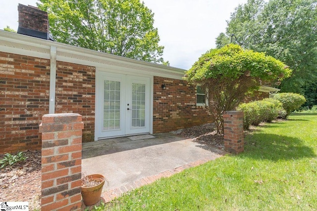 entrance to property featuring french doors and a lawn