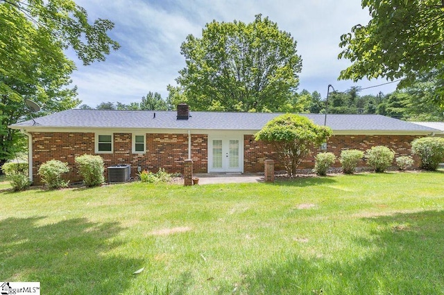 back of property with french doors, a yard, and central air condition unit